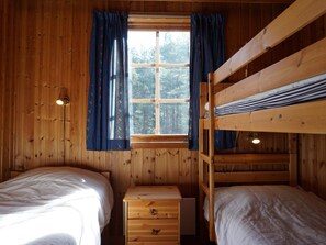 A cabin room with two beds, a wooden dresser, and a window with curtains. - 6 Person Holiday Home in Stromstad (Stromstad)