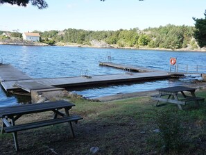A wooden dock extending into a body of water with picnic tables and a lifebuoy on the dock.