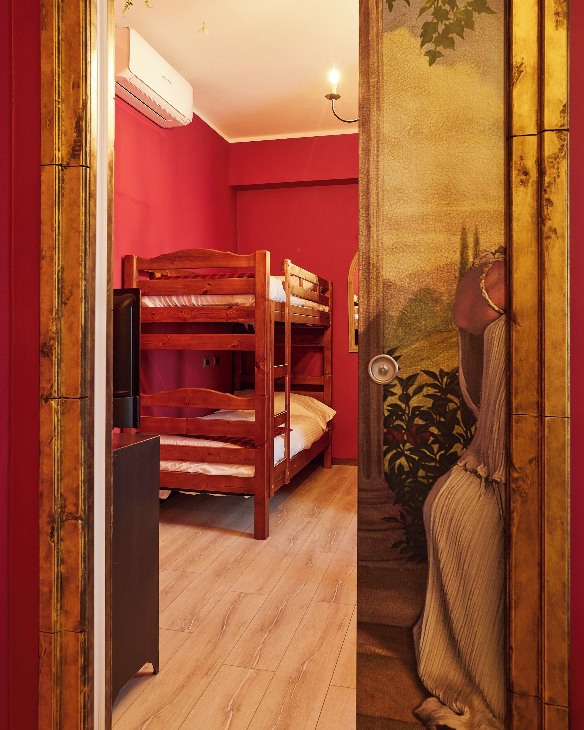 A room with a bunk bed, an air conditioning unit, a small table, and a wall-mounted mirror.