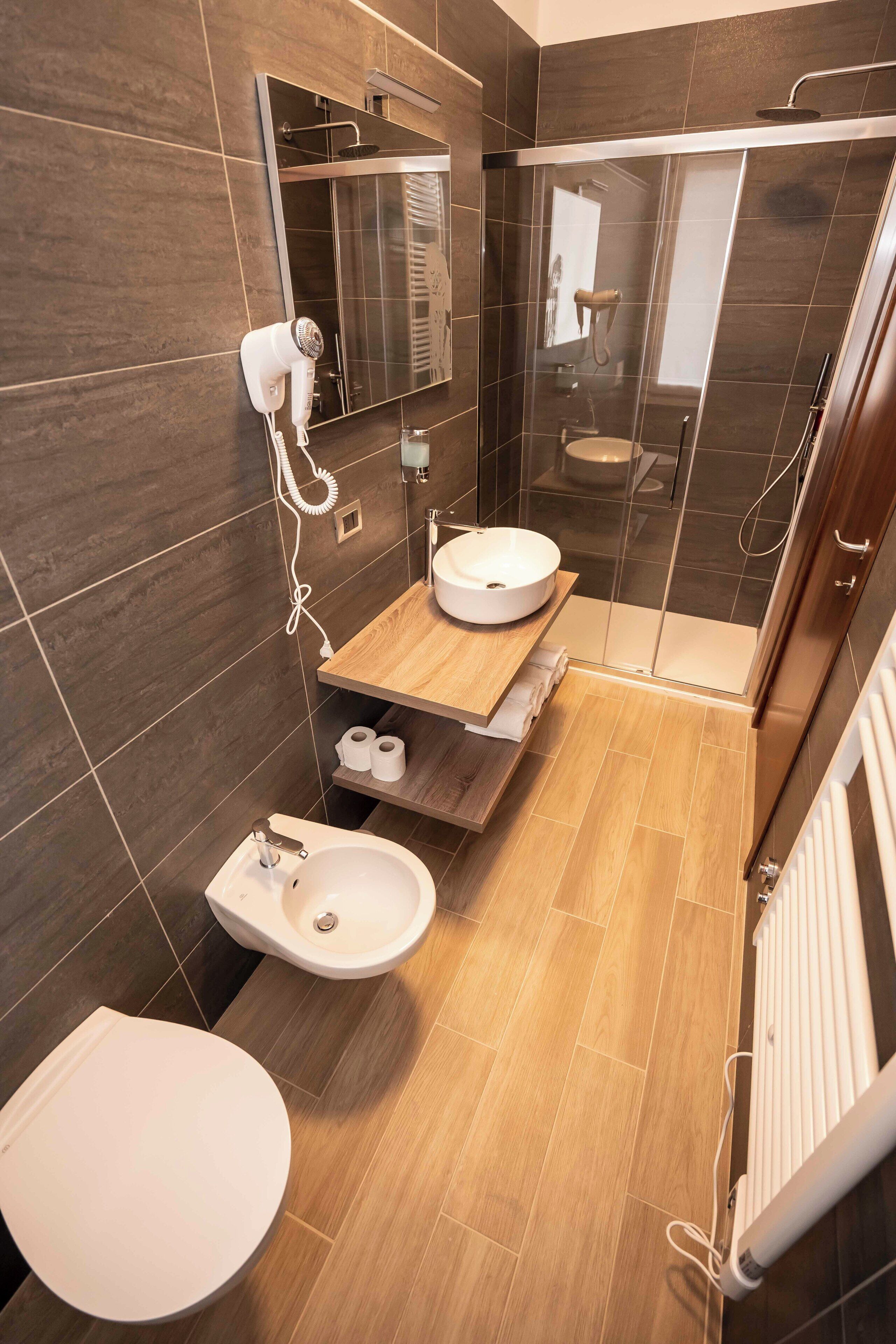A modern bathroom with a shower, sink, and toilet.