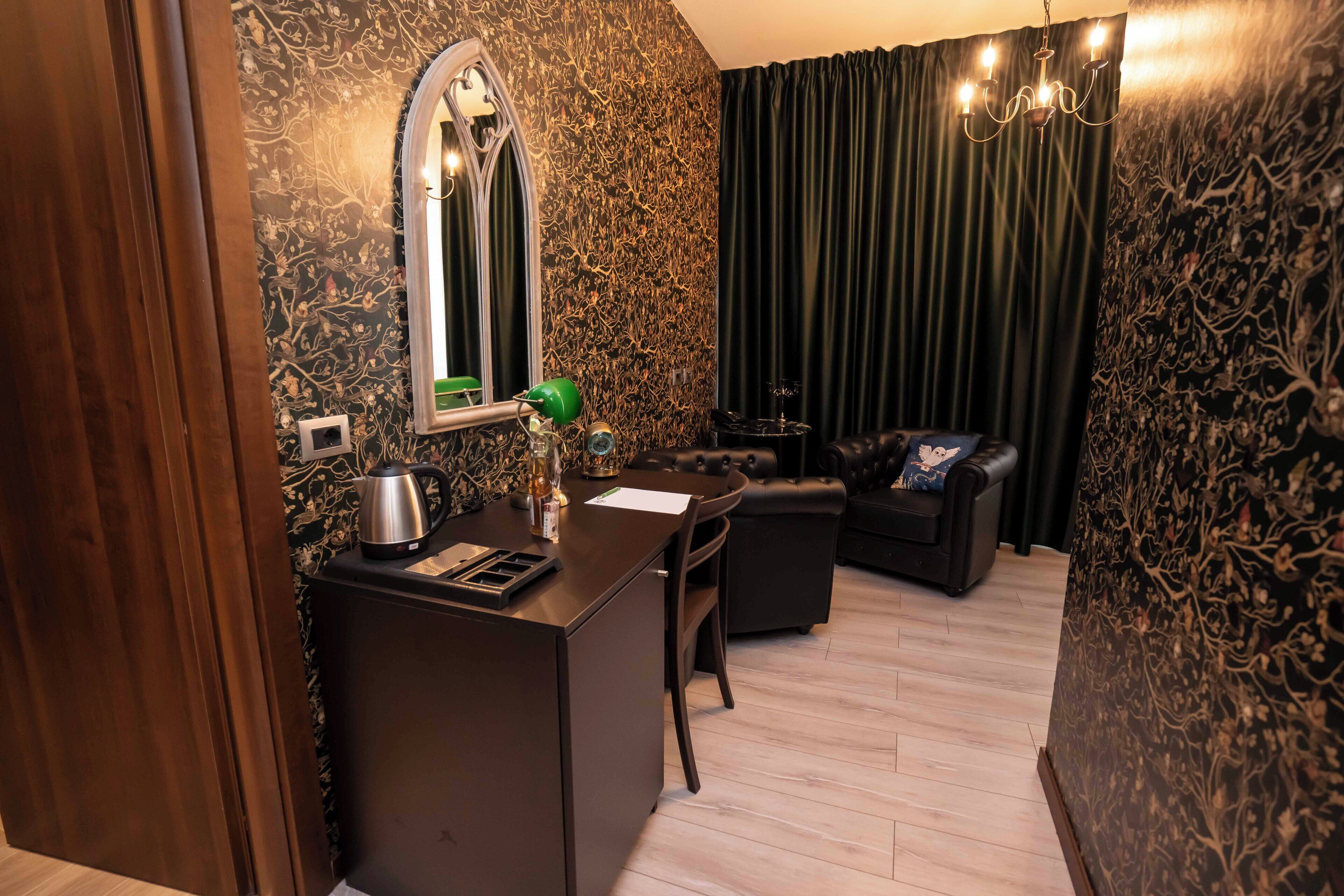 Un espace de vie compact comprenant un bureau en bois foncé, un miroir, un petit coin salon avec un canapé et un lustre.