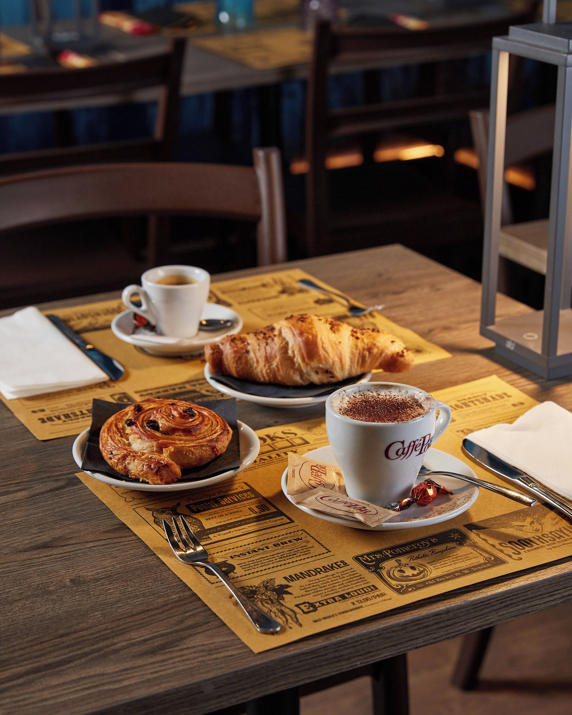 A table with a croissant, a cup of coffee, and a menu.