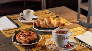 A table with a croissant, a cup of coffee, and a menu.