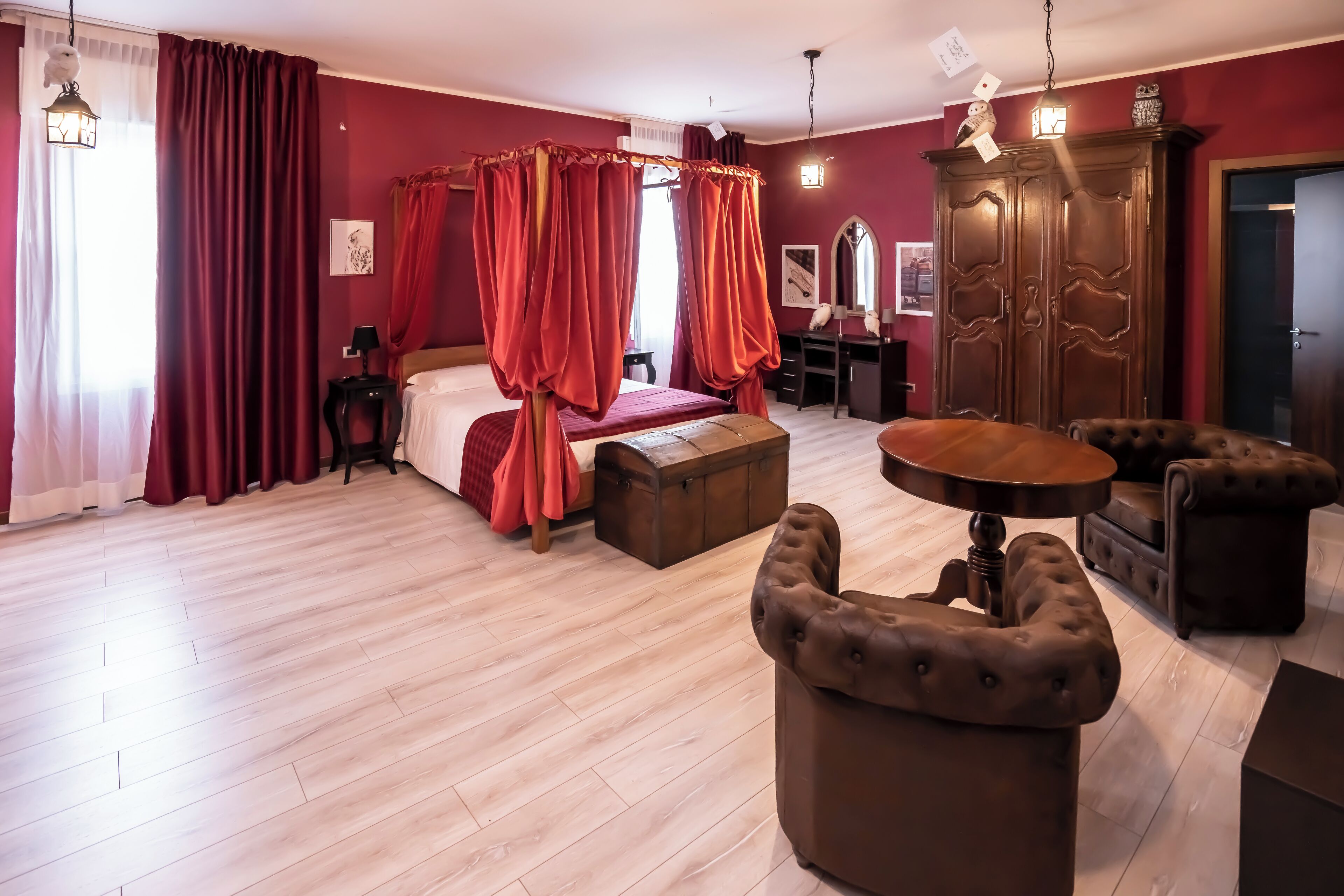 A room with a four-poster bed, a wooden wardrobe, a desk, and a round table.
