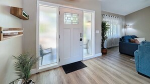 Ein modernes Wohnzimmer mit einem blauen Sofa, Holzboden und einem großen Fenster mit Jalousien.