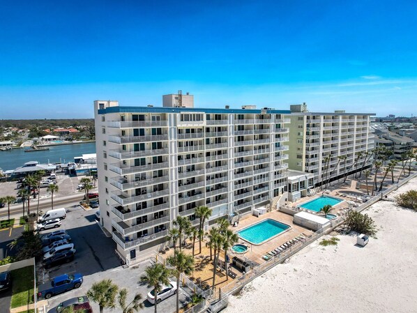 A multi-story hotel with balconies, a swimming pool, and a beach area. - 20002 Gulf Blvd, Penthouse 5 (Indian Shores)