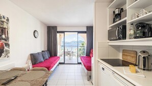 A compact living space with a kitchenette, dining area, and a balcony with a scenic view. - Charming Flat With sea View - 1BR - 2P - Bocca (Cannes)