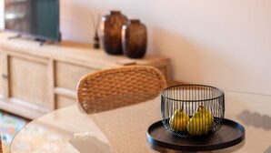 Una mesa de comedor con una cesta de mimbre para fruta que contiene peras, una silla tejida y un armario al fondo.