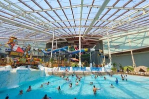 An indoor water park with a large pool, slides, and a covered area. - Private Pocono Oasis | Hot Tub • Sauna • Firepit (Tobyhanna)