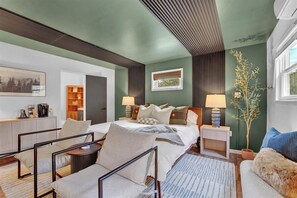 A modern bedroom with a bed, bedside tables, a desk, and chairs. - Private Pocono Oasis | Hot Tub • Sauna • Firepit (Tobyhanna)
