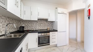Eine moderne Küche mit weißen Schränken, einer schwarzen Arbeitsplatte, einer Edelstahlspüle und einem eingebauten Backofen.