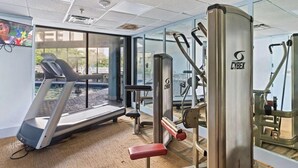 Ett gym med löpband, styrketräningsmaskiner och en spegel.