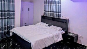Une chambre moderne avec un lit, une table de chevet, un climatiseur et des rideaux.