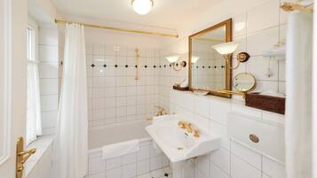 A bathroom with a bathtub, a sink, a mirror, and a shower curtain.