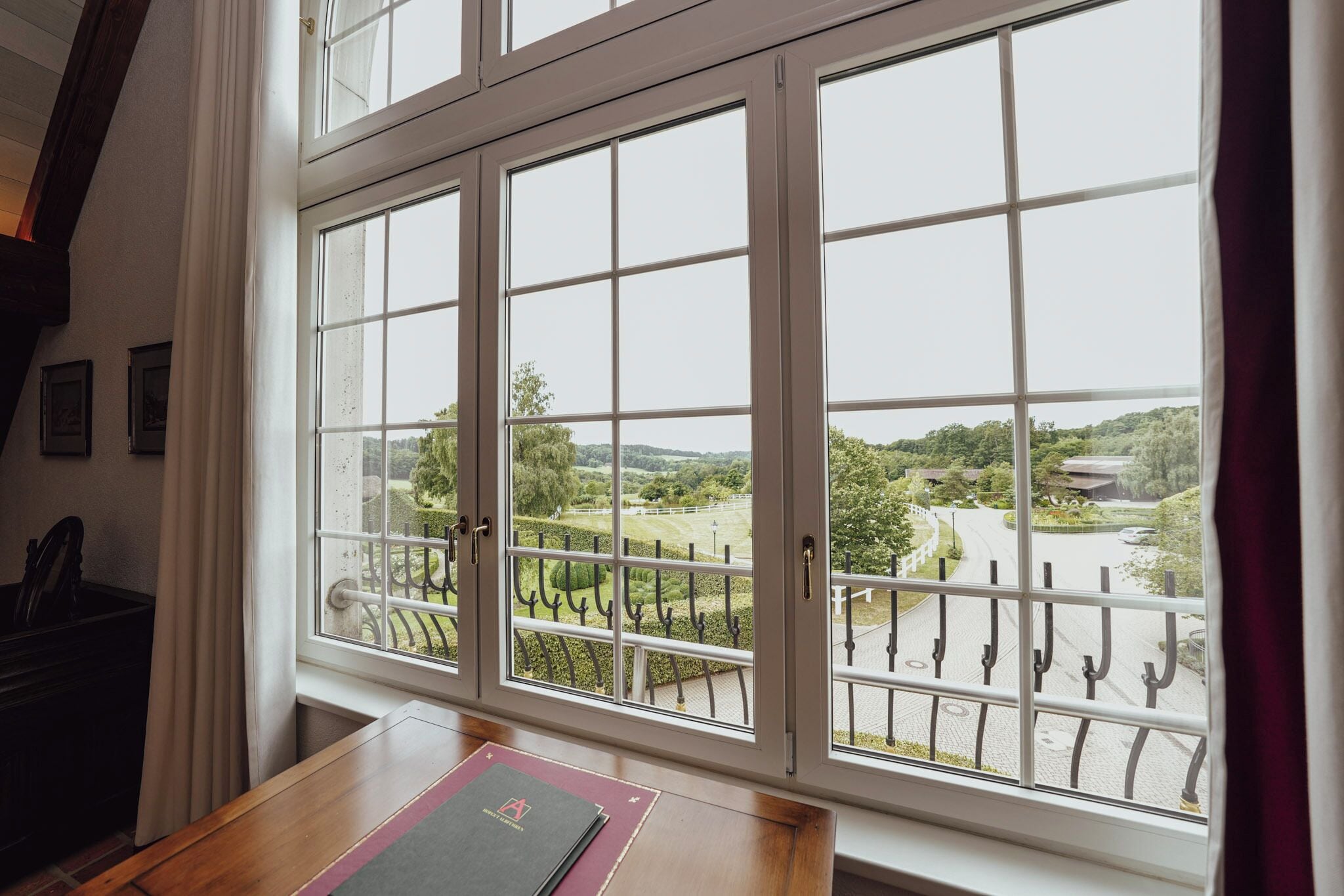 A room with a large window overlooking a landscaped area with a pathway and greenery.