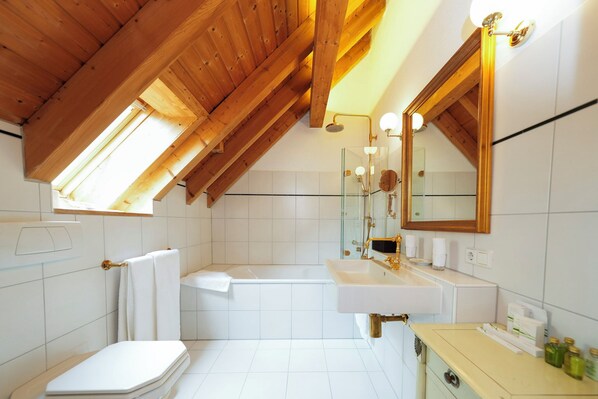 A modern bathroom with a skylight, a bathtub, a toilet, and a vanity with a mirror.