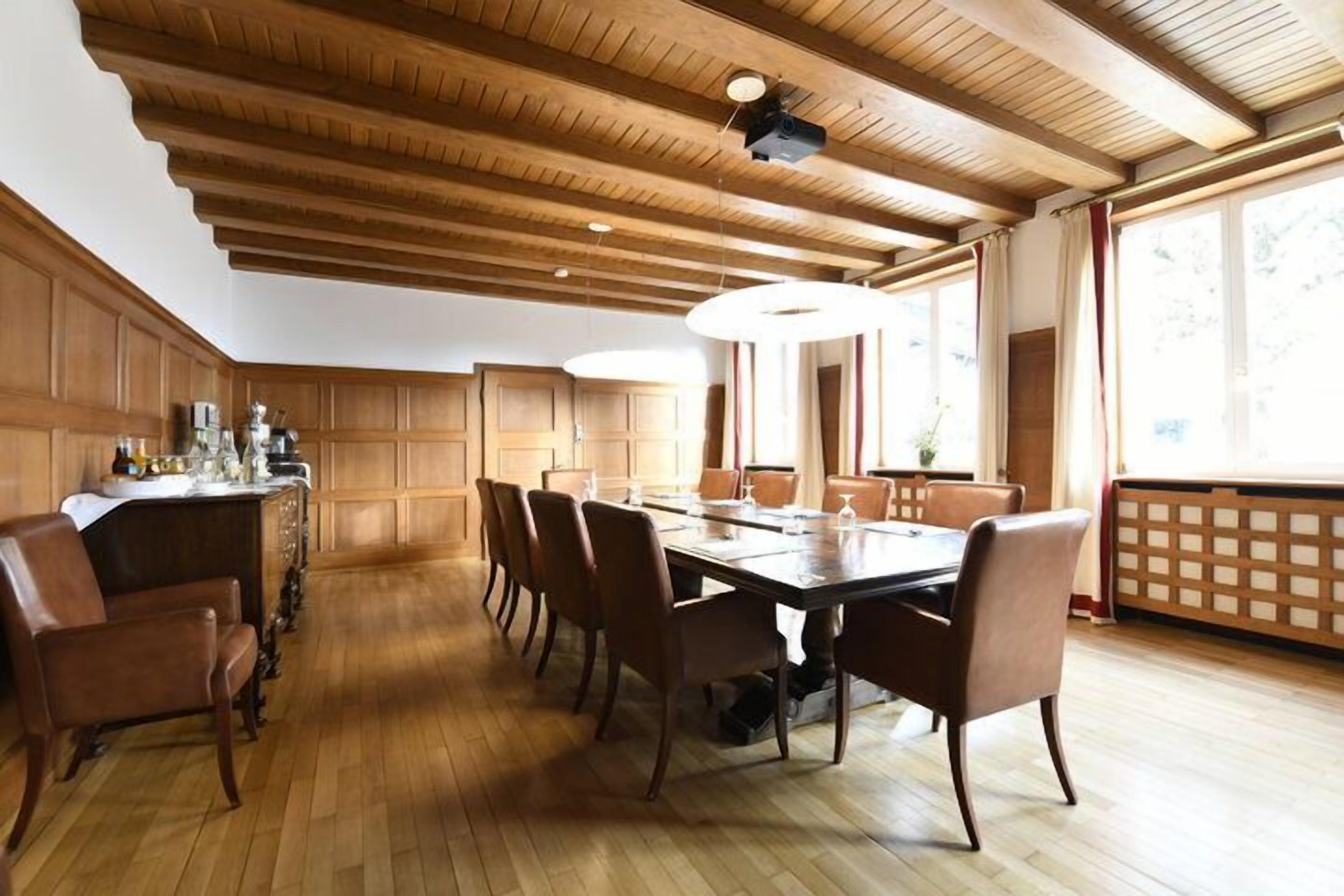 Ein Essbereich mit Holztisch und -stühlen, einer Holzausstattung an der Decke und großen Fenstern.