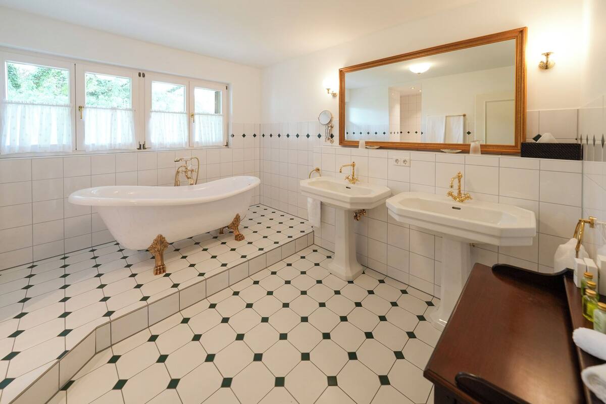 Un baño con una bañera independiente, dos lavamanos y un espejo grande.