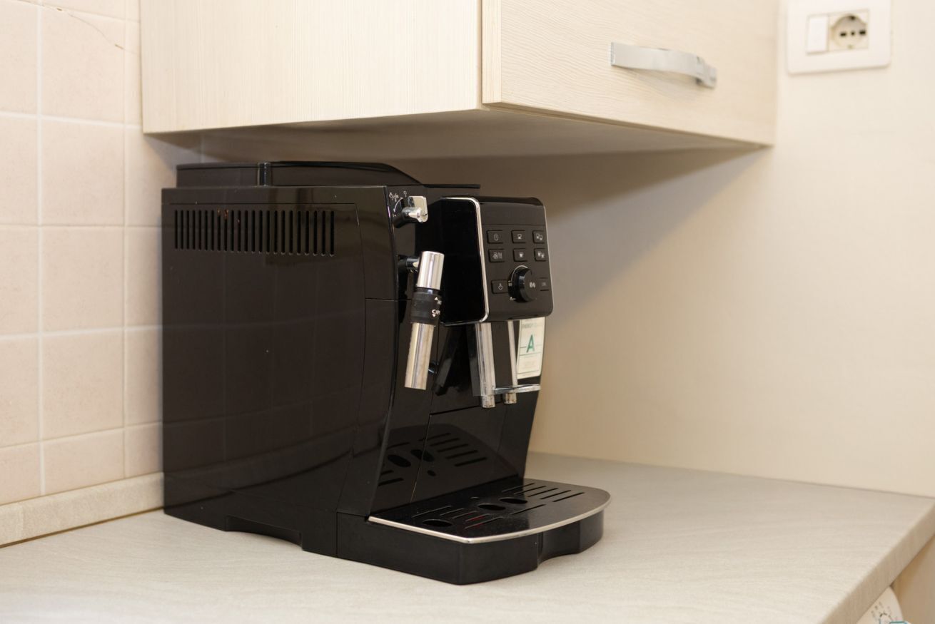 A black coffee machine with a single coffee pot and a control panel, placed on a light-colored countertop.