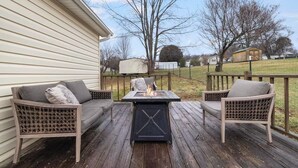 Une terrasse avec deux fauteuils en osier et une table dotée d’un foyer.