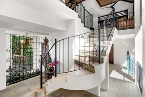 A modern interior with a spiral staircase, white walls, and a view of greenery outside. - Monsoon Villa A—Central Balinese-style Pool Oasis (Port Douglas)