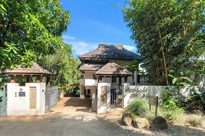A gated entrance to a building with a tiled roof, surrounded by lush greenery.