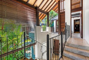 A staircase with a metal railing leading to a covered outdoor area with wooden beams and a view of greenery.