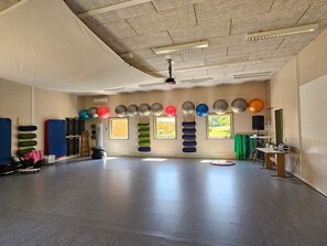 A spacious room with a high ceiling, padded mats, and exercise balls arranged against the walls. - 1 Person Holiday Park Home in Lemvig (Lemvig)