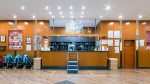 A reception area with a wooden counter, a ladder, and a wall with framed photos and certificates.