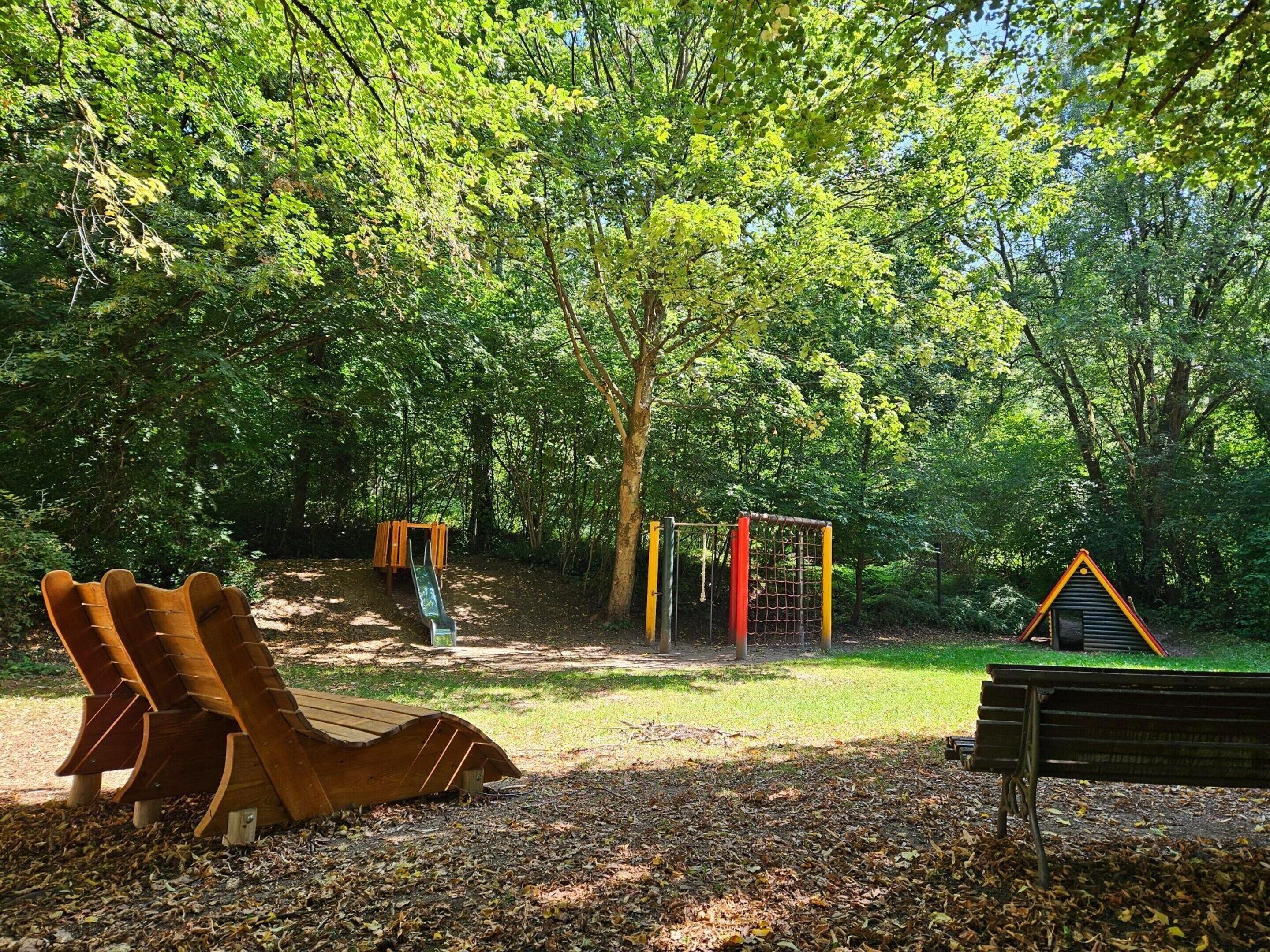 Un parque con un columpio de madera, un tobogán y un banco.