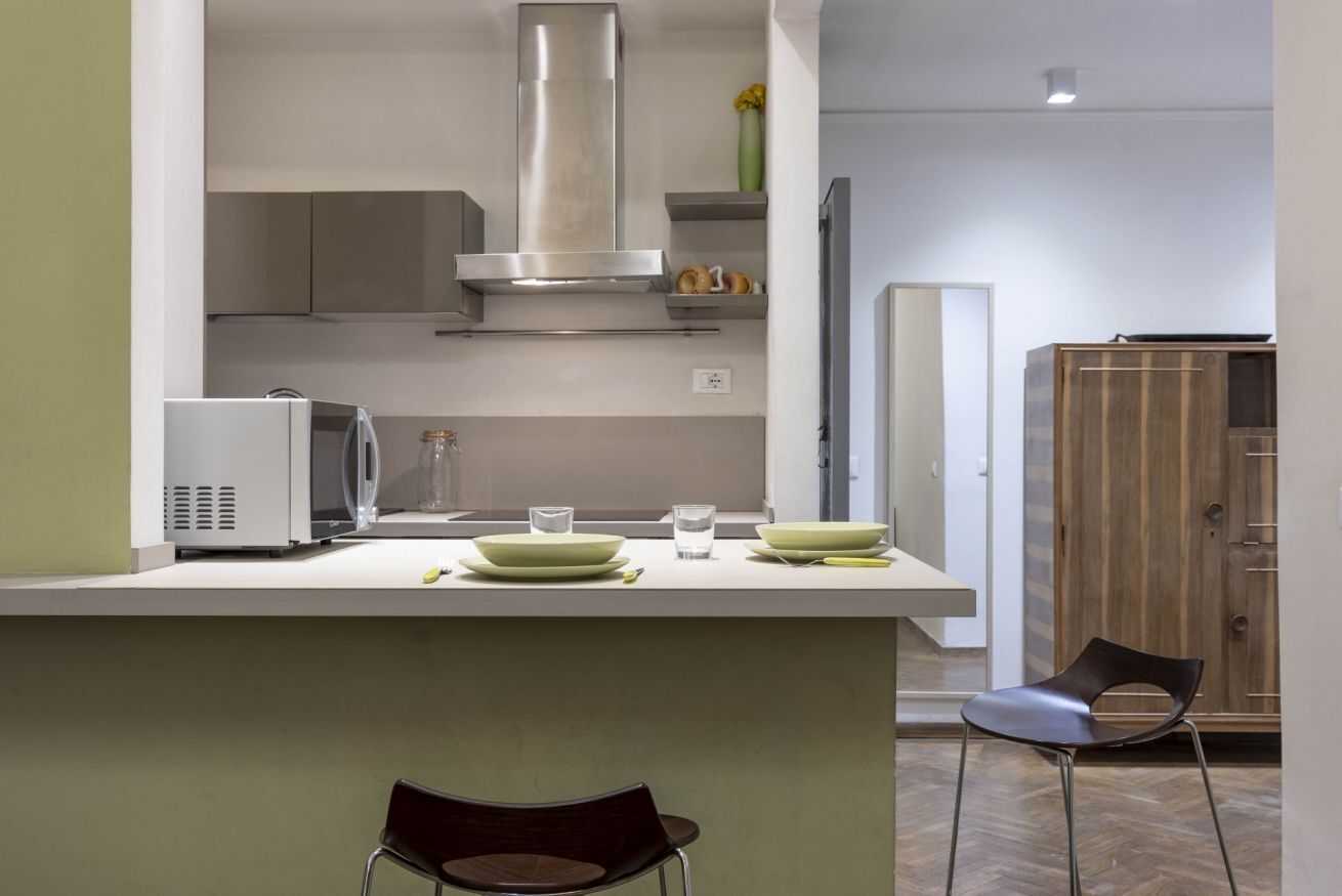 Une cuisine moderne dotée d’un îlot central, de meubles de rangement intégrés et d’une hotte en acier inoxydable.
