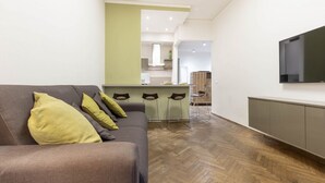 Un soggiorno moderno con un divano, una televisione e un'area cucina sullo sfondo.