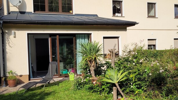 A house with solar panels, a satellite dish, and a garden with a lawn chair. - Cozy newly built vacation apartment in quiet wooded surroundings (Dippoldiswalde)