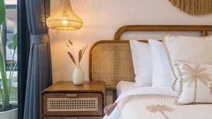 A neatly arranged bedroom with a bed, bedside table, lamp, and a view of the outdoors. - Villa CanSavina - 3 Rooms - Center Of Seminyak (Bali)