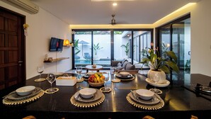 A modern dining area with a black countertop, white plates, and a bowl of fruit. - Villa CanSavina - 3 Rooms - Center Of Seminyak (Bali)