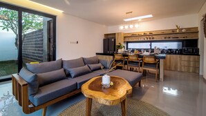 A modern living room with a sofa, dining area, and kitchen. - Villa CanSavina - 3 Rooms - Center Of Seminyak (Bali)