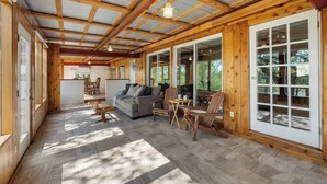 A spacious indoor area with a wooden ceiling, a sofa, chairs, and a dining table. - Lakefront Retreat: Private Dock | King Bedrooms (Burnet County)