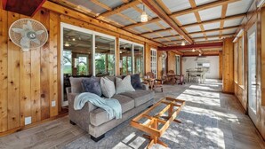A cozy interior with a wooden ceiling, a sofa, a fan, and a dining area. - Lakefront Retreat: Private Dock | King Bedrooms (Burnet County)