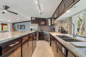 Una cocina moderna con armarios de madera oscura, encimera de mármol, horno empotrado y un amplio ventanal que proporciona luz natural.