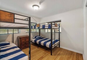 Habitación con literas, un aparador de madera y un ventilador de techo.