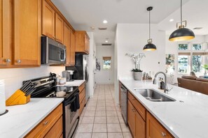 A modern kitchen with wooden cabinets, stainless steel appliances, and a white countertop. - Tee Box Retreat at Lakecliff Country Club (Travis County)