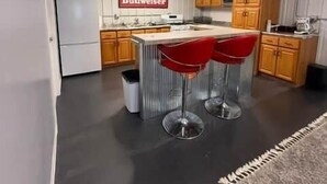 Una cocina moderna con una isla central, armarios de madera y un televisor montado.