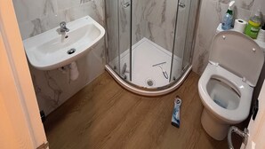 A bathroom with a glass-enclosed shower, a sink, and a toilet. - Deluxe Twin Room with Shared Kitchen & Bathroom Access - For 2 Guests (London)