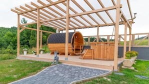A wooden structure with a covered area and a barrel-shaped building. - Cottage in Duszniki Near Ski Slopes (Szczytna)