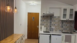 A modern kitchen with a wooden dining table, white cabinets, and patterned backsplash. - Modern Studio with private Bathroom & Kitchenette in 3 bed apartment (London)