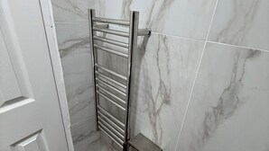 A bathroom with a marble wall, a chrome towel rack, and a wooden floor. - Modern Studio with private Bathroom & Kitchenette in 3 bed apartment (London)