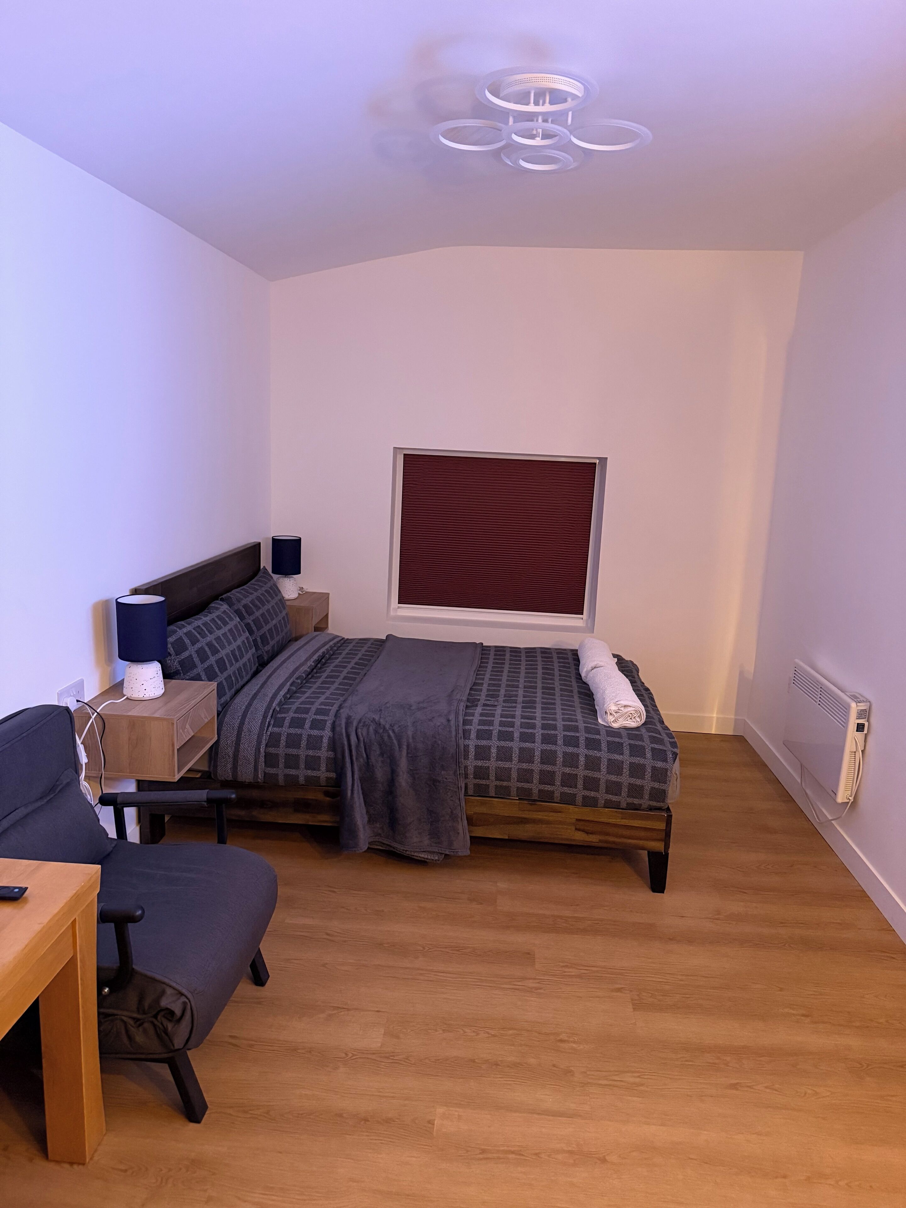 Une petite chambre à coucher moderne, comprenant un lit, des tables de chevet, une chaise et un bureau.