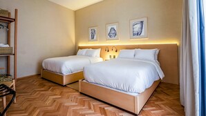 Een hotelkamer met twee bedden, een houten vloer en kunstwerken aan de muur.