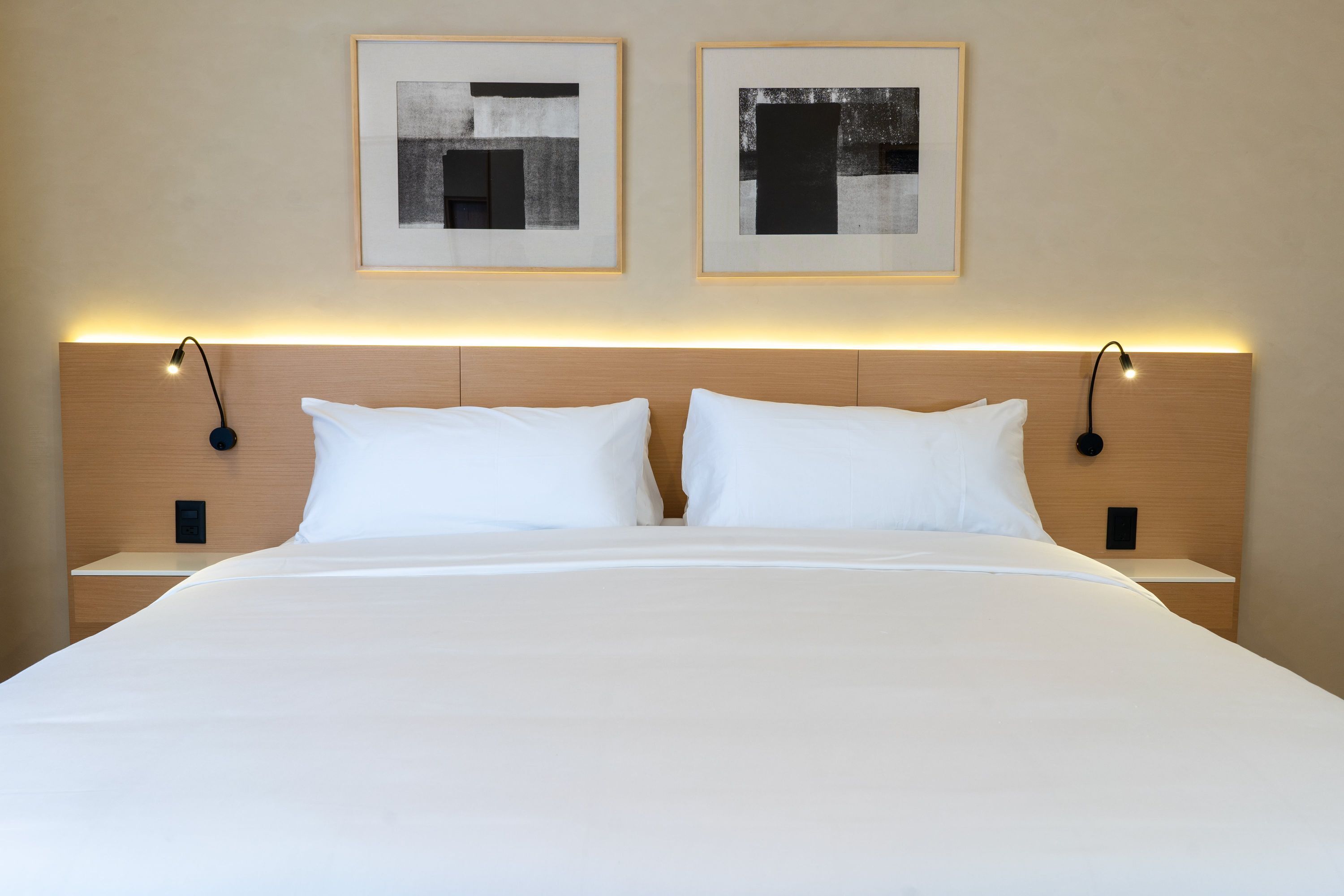 Hotellihuone, jossa on suuri sänky, kaksi yöpöytää ja kaksi seinälle asennettua lamppua.