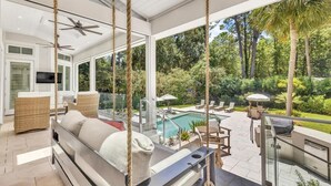 Un espacio exterior moderno con piscina, mobiliario y vistas a la vegetación circundante.